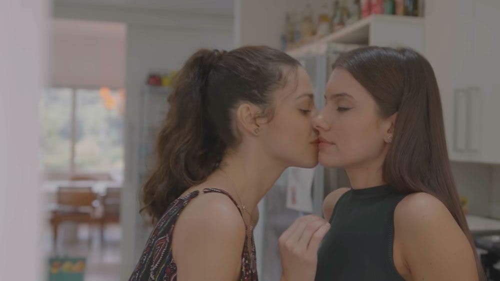 Luiza besando a Valentina en la esquina de la boca