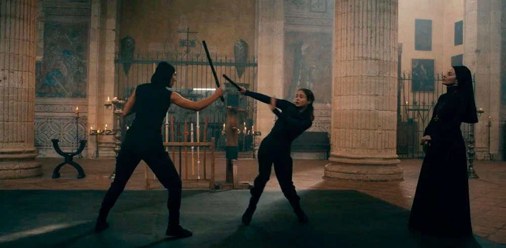 Lilith y Ava entrenando mientras las mira la Madre Superiora