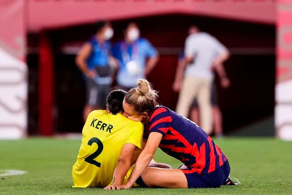 Kristie Mewis y Sam Kerr sentadas en un campo de fútbol